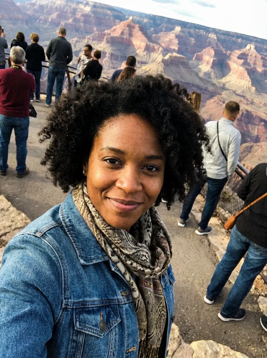 Travel selfie of a woman in a denim jacket and patterned scarf at the Grand Canyon